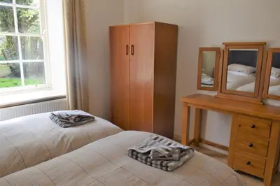 a bedroom with two beds and a dresser and a mirror at The Stables in Carsethorn