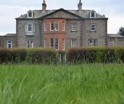 an old house in a field of tall grass at The Stables in Carsethorn