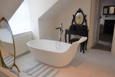 a white bath tub in a bathroom with a mirror at Coachmans Cottage in Carsethorn