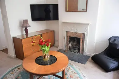 a living room with a table with a vase of flowers on it at Coachmans Cottage in Carsethorn