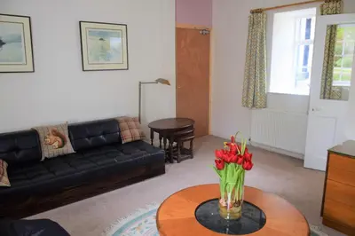 a living room with a couch and a table with flowers at Coachmans Cottage in Carsethorn