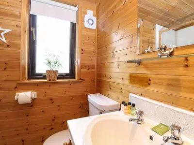 a bathroom with a sink and a toilet and a window at Derwent Lodge in Keswick