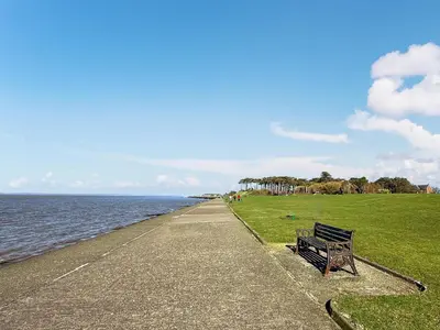 a bench sitting on the side of a sidewalk near the water at The Court House - Uk43908 in Silloth