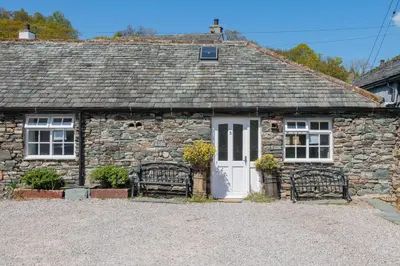 a stone cottage with two benches in front of it at Cottage 5 mews Studio in Keswick
