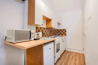 a small kitchen with white cabinets and a microwave at Cottage 5 mews Studio in Keswick