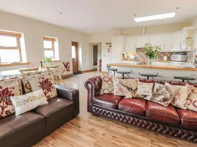 a living room with two brown leather couches and a kitchen at Laird House in Lockerbie