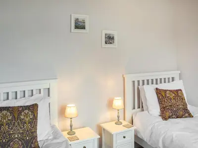 a bedroom with two beds and two lamps on tables at Winlocke Cottage in Leadhills