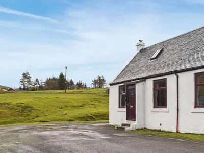 a small white building with a field in the background at Winlocke Cottage in Leadhills