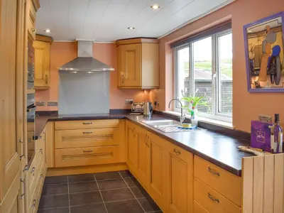 a kitchen with wooden cabinets and a sink and a window at Winlocke Cottage in Leadhills