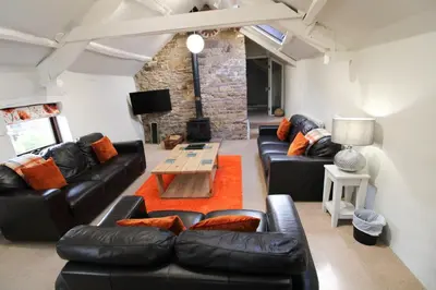 a living room with black leather couches and a table at Brae Fell Cottage, Sebergham, Nr Caldbeck dog friendly and hot tub in Sebergham