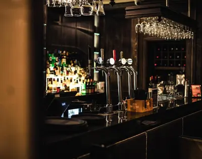 a bar with a counter with bottles of alcohol at The Fenwick Hotel in Kilmarnock