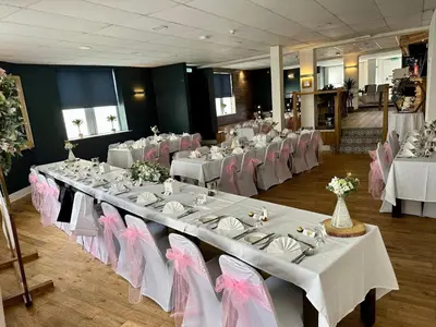 a banquet hall with white tables and pink chairs at Waverley Hotel in Workington
