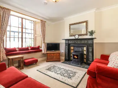 a living room with a fireplace and red furniture at Primrose Cottage in Keswick