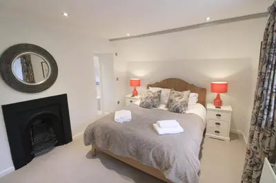 a bedroom with a bed with a fireplace and a mirror at Calley House, Hutton remote cottage with hot tub, 10 minutes to Ullswater in Penruddock