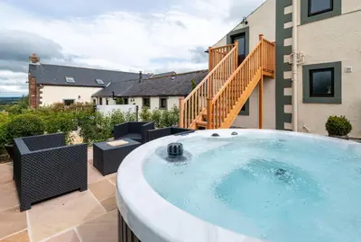 a hot tub on the patio of a house at Chapel Beck, Nr Caldbeck ideally family accommodation with hot tub in Sebergham