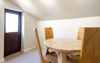 a wooden table and chairs in a room with a door at Chapel Beck, Nr Caldbeck ideally family accommodation with hot tub in Sebergham