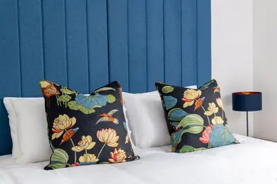 a bed with two pillows and a blue wall at Daffodil, Penruddock Eco & dog friendly lodge with hot tub in Penruddock