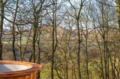 a view of the mountains from a hot tub in the woods at Daffodil, Penruddock Eco & dog friendly lodge with hot tub in Penruddock