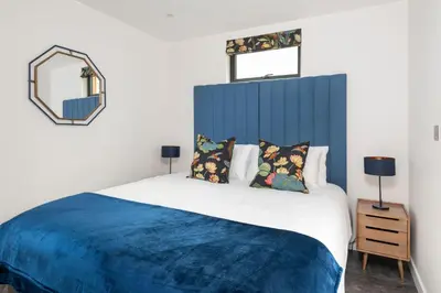 a bedroom with a large bed with a blue headboard at Daffodil, Penruddock Eco & dog friendly lodge with hot tub in Penruddock