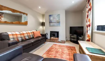 a living room with a leather couch and a tv at Fisher Gill, Sebergham, Close to Caldbeck Fells with hot tub in Sebergham