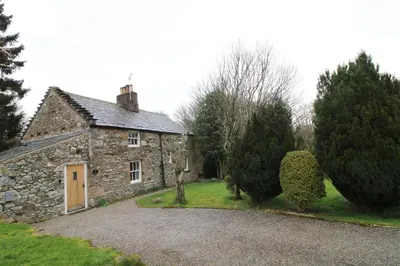 an old stone house with trees in front of it at Red Squirrel Cottage, Hutton luxurious cottage in a rural setting 10 minutes to Ullswater 15 minutes to Keswick in Penruddock