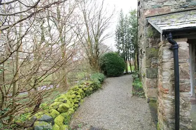 a stone building with a path next to a stone wall at Red Squirrel Cottage, Hutton luxurious cottage in a rural setting 10 minutes to Ullswater 15 minutes to Keswick in Penruddock