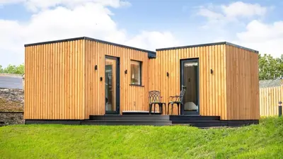 a small wooden house on a grassy hill at Ruecroft, Penruddock an Eco & dog friendly lodge with a hot tub, 10 minutes from Lake Ullswater in Penruddock