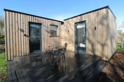 a house with two chairs and a table on a deck at Ruecroft, Penruddock an Eco & dog friendly lodge with a hot tub, 10 minutes from Lake Ullswater in Penruddock