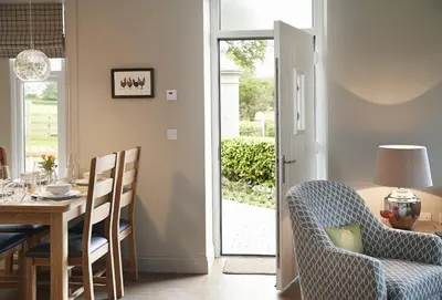 a dining room with a table and a chair and a table and a door at Netherwood Lodge in Dumfries