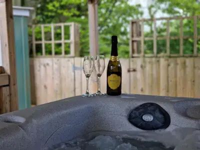 a bottle of wine and two wine glasses on a table at Cottage - Sleeps 3 hot tub & pet friendly in Carlisle