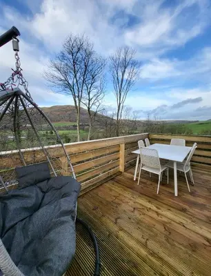 a patio with a table and chairs on a wooden deck at FAB Caravan Holiday Home in Colmonell