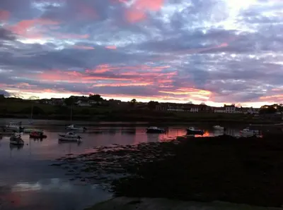 a sunset over a river with boats in the water at 3 bedroom townhouse right on the harbour in Isle of Whithorn