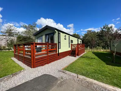 a small green house with a wooden fence at Elite Holiday Caravan in Bassenthwaite