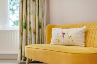 a yellow couch with a pillow on it with a window at Redwood Rise Apartment Keswick at The Lairbeck in Keswick