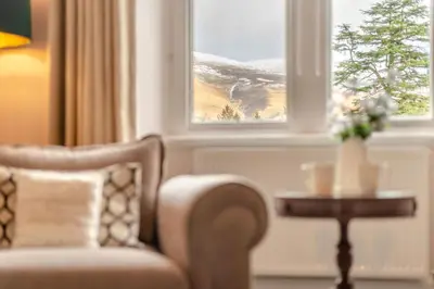 a living room with a chair and a table and a window at Cameron Fell Apartment Keswick at The Lairbeck in Keswick