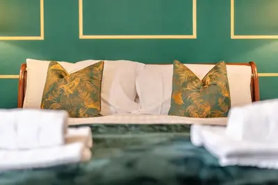 a bed with two pillows and a green wall at Cameron Fell Apartment Keswick at The Lairbeck in Keswick