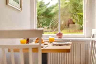 a table with two glasses of orange juice and a window at Bethby Beck Apartment Keswick at The Lairbeck in Keswick