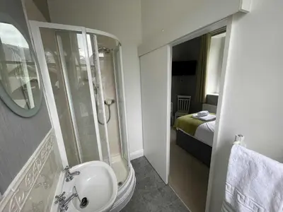 a bathroom with a sink and a shower and a bed at The Capsule Room at The Lairbeck in Keswick in Keswick