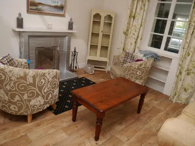 a living room with two chairs and a table and a fireplace at The Drovers Cabin in Kirkcudbright