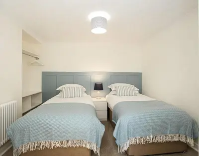 two twin beds in a room with a lamp at 118 High Street in Kirkcudbright