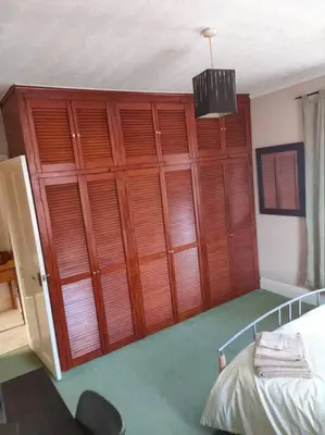 a room with a large wooden closet with a bed at Family Home Near City Centre - New KING bed! in Carlisle