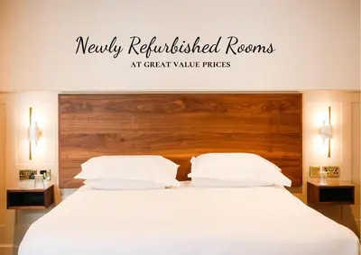 a bedroom with a white bed with a wooden headboard at Allerdale Court Hotel in Cockermouth