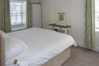 a bedroom with a white bed and a mirror at Skerrow in New Galloway