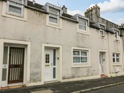a house with white doors and windows on a street at Barley Cottage in Newton Stewart