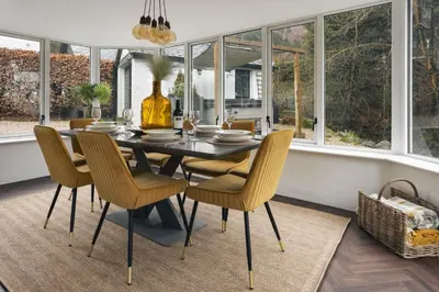 a dining room with a table and chairs and windows at Bellfoot Rural Retreat and Hot Tub in Grasmere