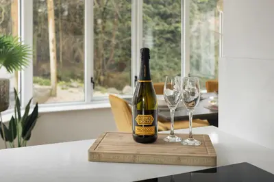 a bottle of wine on a cutting board with two wine glasses at Bellfoot Rural Retreat and Hot Tub in Grasmere