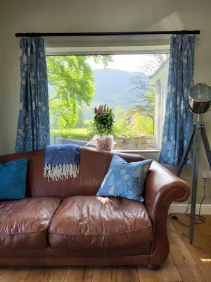 a brown leather couch sitting in front of a window at Lingmoor Cottage in Chapel Stile