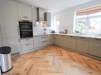 a kitchen with white cabinets and a wooden floor at Limhus House in Keswick