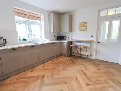 a kitchen with white cabinets and a wooden floor at Limhus House in Keswick