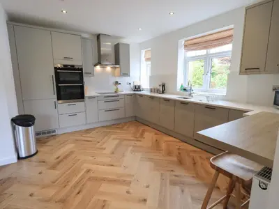 a kitchen with white cabinets and a wooden floor at Limhus House in Keswick